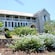 Tropical foliage fronts the entrance of 2 story stone plantation home with a verandah on second floor